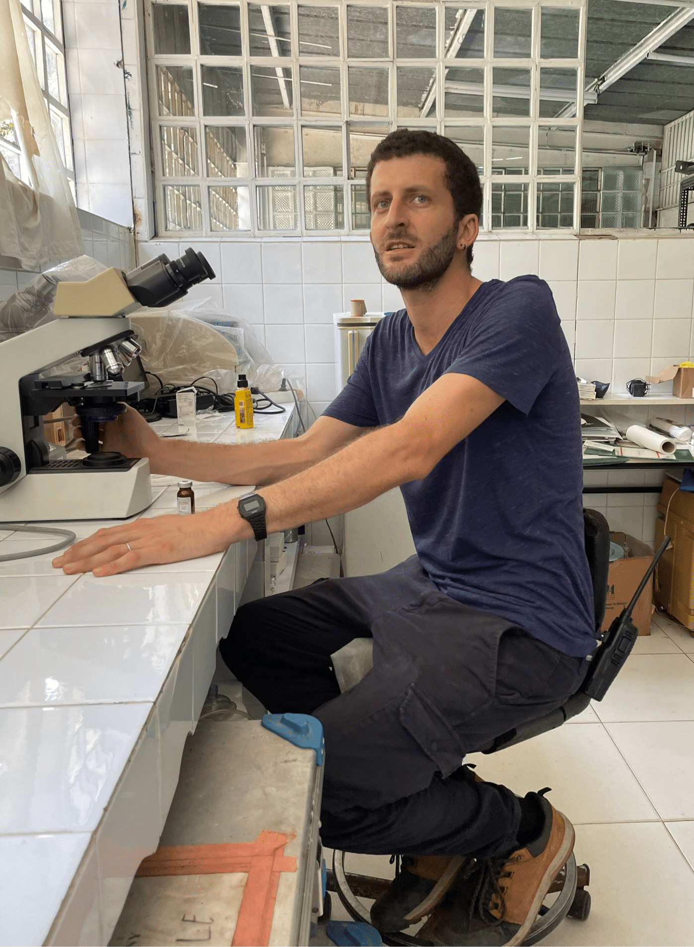 Veterinarian Raphael Belais sits at table with microscope in infirmary at Lola ya Bonobo sanctuary