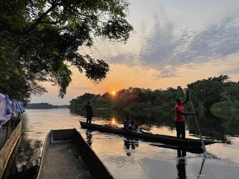 Community members on dug out canoe passing Ekolo Ya Bonobo