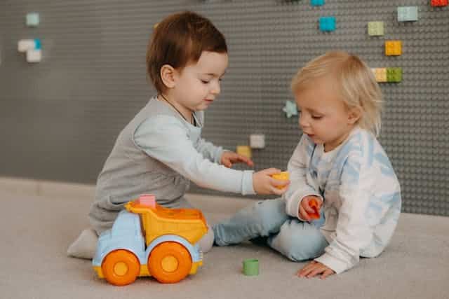 Babies playing. One handing toy to other. Credit: Polesie Toys